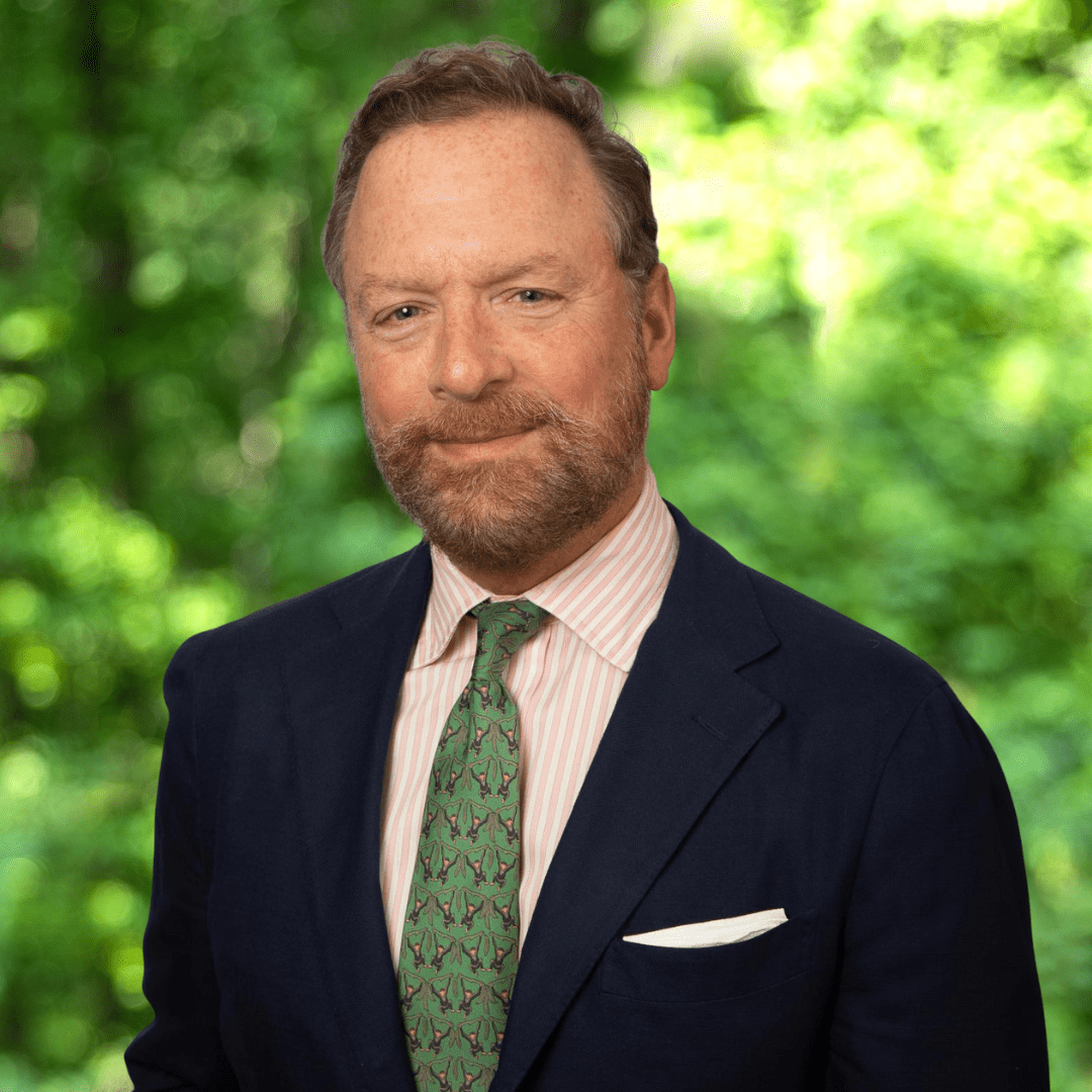 Headshot of Councilor Gregory W. Tucker. Man smiling with dark suit, white collared shirt and green necktie