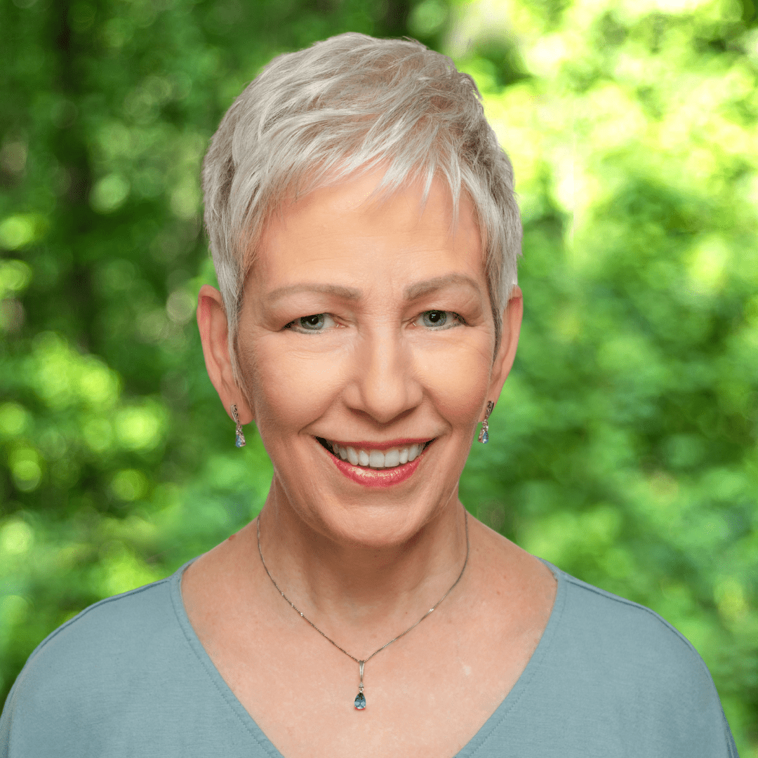 headshot of janet stanford - woman smiling with light blue blouse and short gray hair