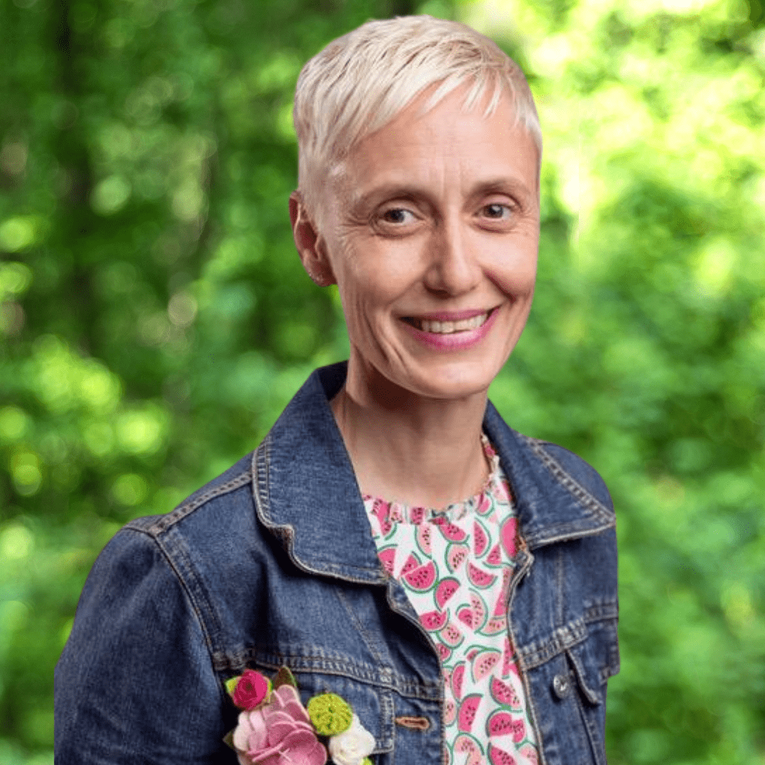 Kathy Beachler headshot. Woman smiling with denim jacket and multicolored shirt. 