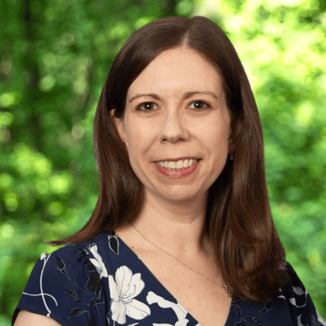 Laura Weiss headshot. Smiling woman with dark hair wearing a dark, floral-patterned top
