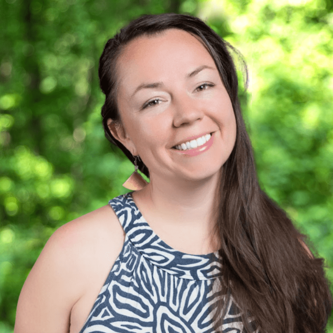 Nora Howell headshot. Smiling woman with long, brown hair and patterned black and white top