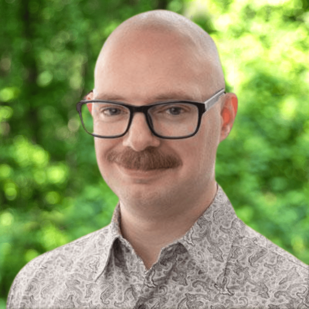 Ryan Koons headshot. Man smiling with dark glasses and a multicolored shirt.