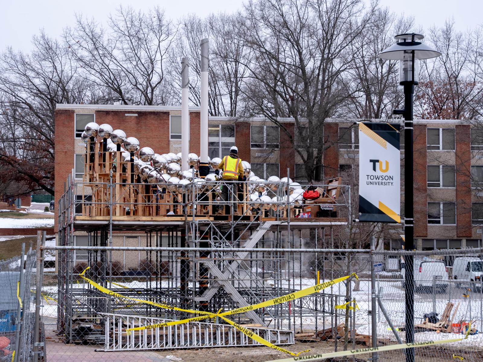 worker in yellow construction vest installating of public art sculpture on scaffolding